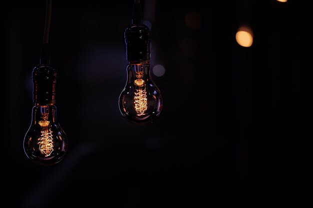 Duas lâmpadas luminosas penduradas no escuro da boke. Conceito de decoração e ambiente.