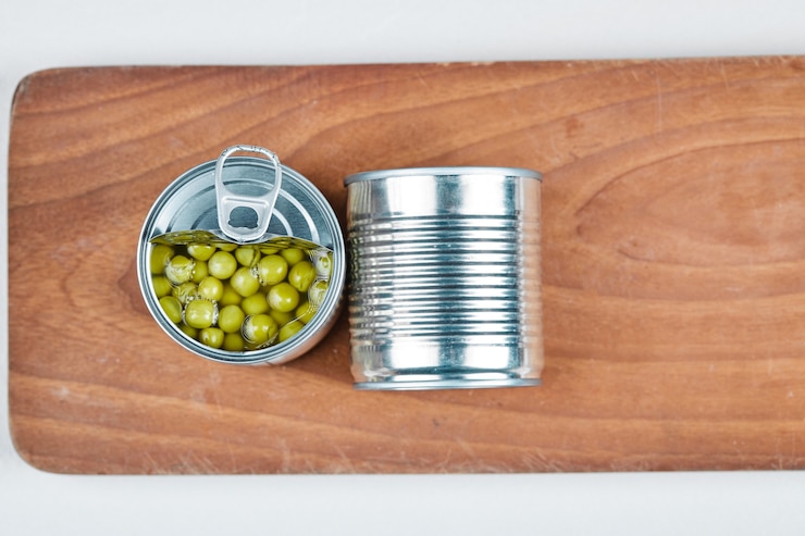 Foto grátis duas latas de ervilhas cozidas em uma placa de madeira.