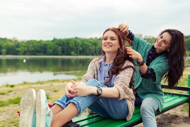 Duas lindas meninas relaxantes ao fazer o penteado, aproveitando o tempo juntos