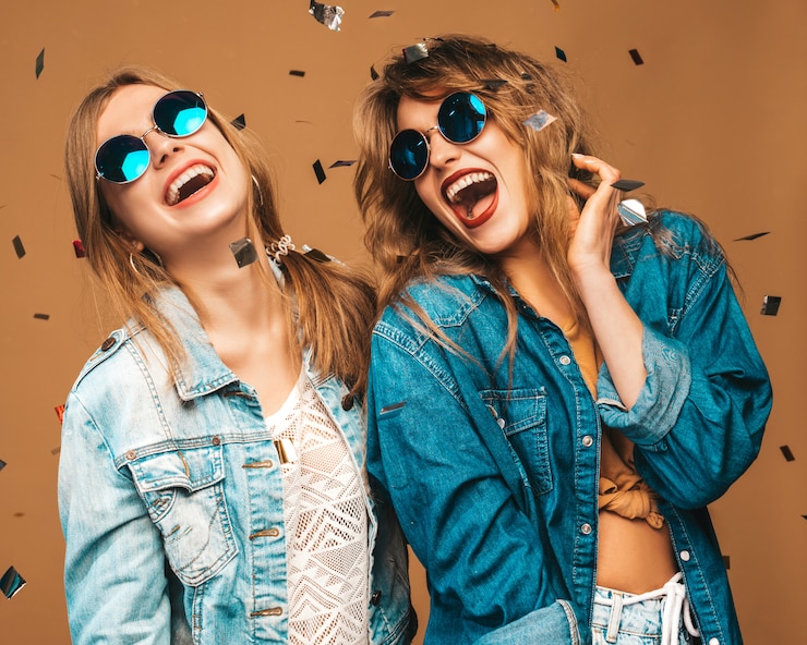 Foto grátis duas lindas meninas sorridentes em roupas da moda no verão e óculos de sol. mulheres sexy despreocupadas posando. modelos de gritos positivos sob confetes