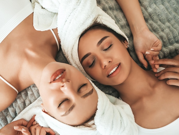 Duas lindas mulheres sorridentes com roupões de banho brancos e toalhas na cabeça