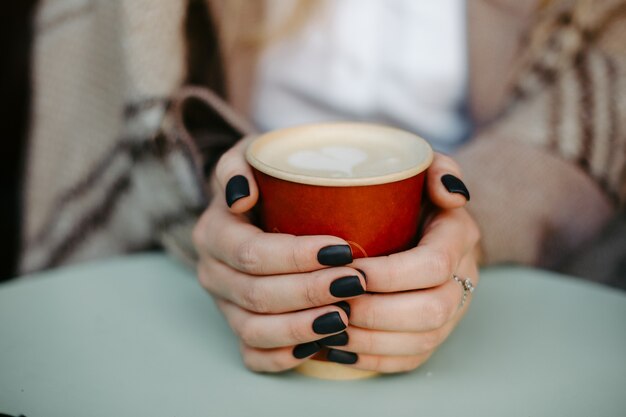 Duas mãos femininas segurando uma xícara de café com café