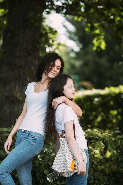 Duas meninas abraçando relaxando de pé ao ar livre