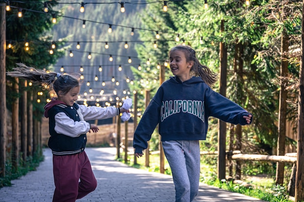 Duas meninas dançam na floresta em um fundo desfocado com lâmpadas