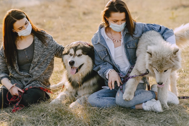 Duas meninas elegantes em um campo ensolarado com cães