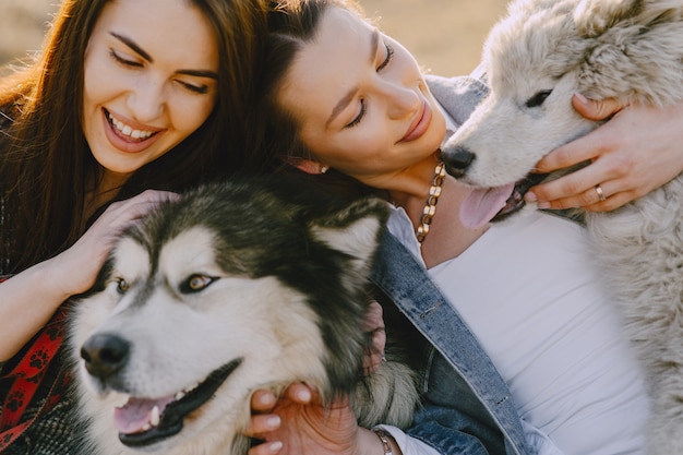 Duas meninas elegantes em um campo ensolarado com cães