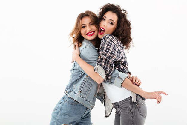 Duas meninas felizes, abraçando-se ao longo da parede branca