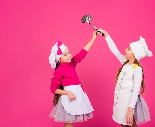 Duas meninas felizes cozinha em pé com conchas