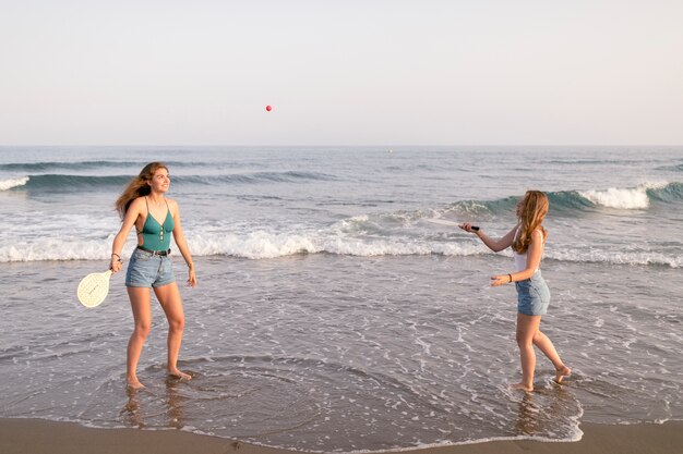 Duas meninas, jogando tênis, em, litoral