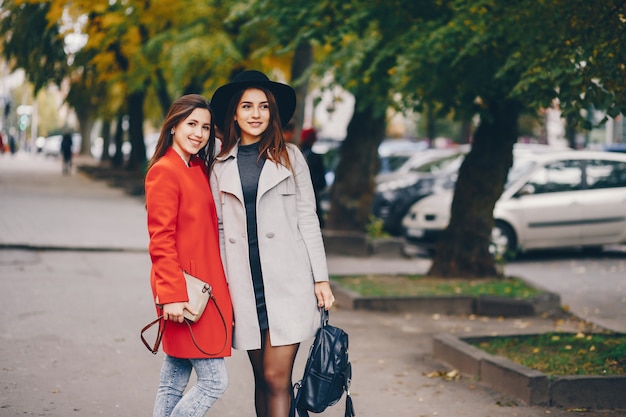 duas meninas jovens e bonitas andando em uma cidade de outono