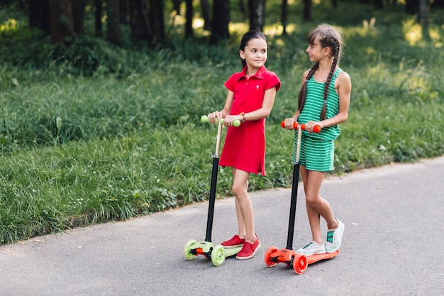 Duas meninas, montando, pontapé scooter, em, rua