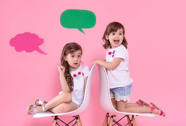 Foto grátis duas meninas na parede colorida com ícones do discurso