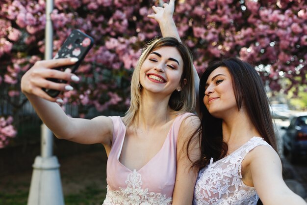 Duas meninas tomar selfie antes de uma árvore linda sakura no parque