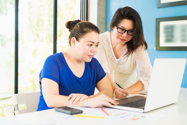 Duas mulheres de negócios estão trabalhando com o computador no escritório