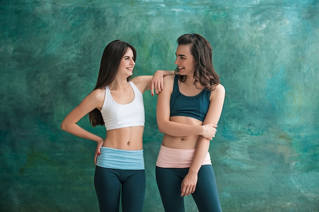 Duas mulheres desportivas jovens posando no ginásio.