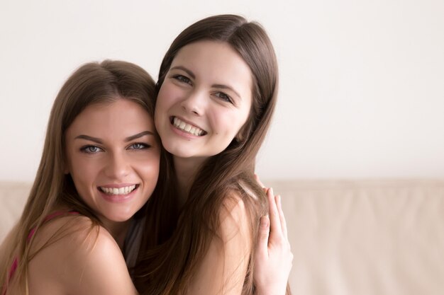 Duas mulheres felizes abraçando e olhando na câmera