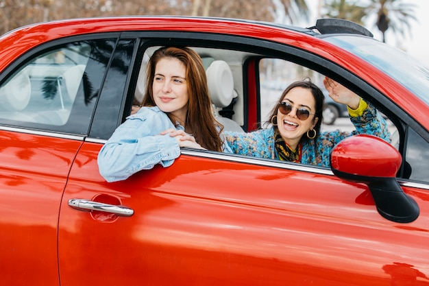 Duas mulheres felizes, olhando para fora da janela do carro