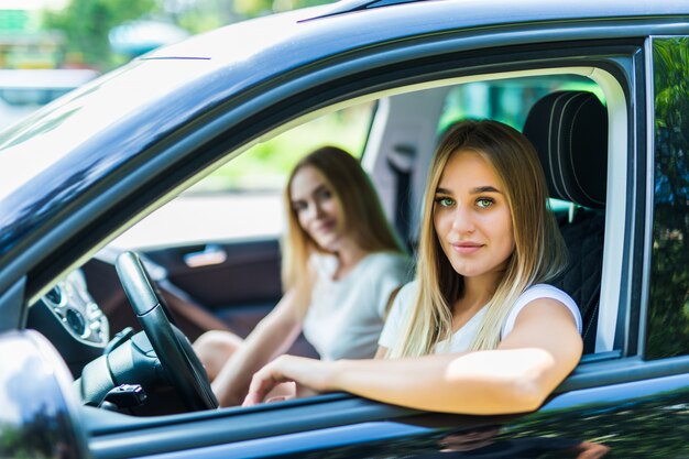 Duas mulheres jovens em viagem de carro, dirigindo o carro e tirando sarro. Emoções positivas.