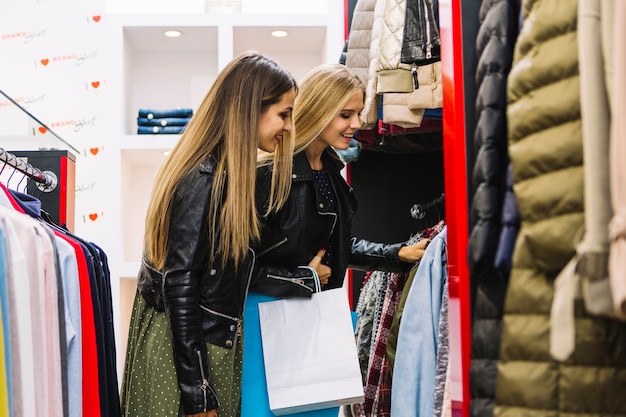 Duas mulheres jovens loiras olhando roupas na loja de compras