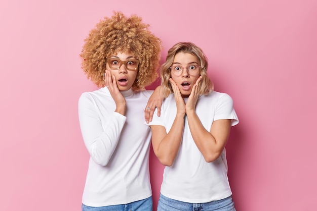 Foto grátis duas mulheres jovens suspiram de surpresa olhando chocadas em roupas casuais isoladas sobre fundo rosa senhoras espantadas ouvem notícias emocionantes reações de emoções e conceito de expressões de rosto humano