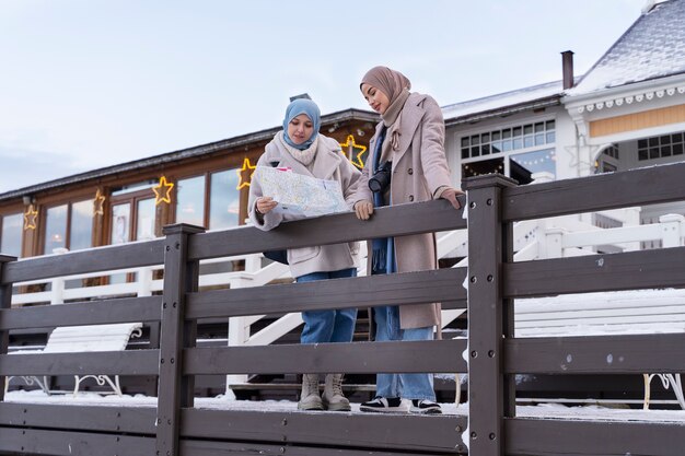 Duas mulheres muçulmanas com hijabs consultando o mapa durante a viagem