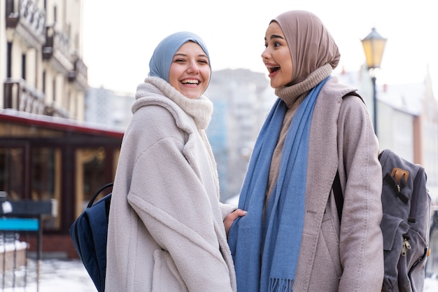 Duas mulheres muçulmanas com hijabs sorrindo enquanto viajam na cidade