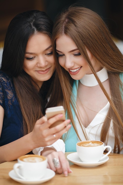 duas mulheres muito jovens no café com café e telefone