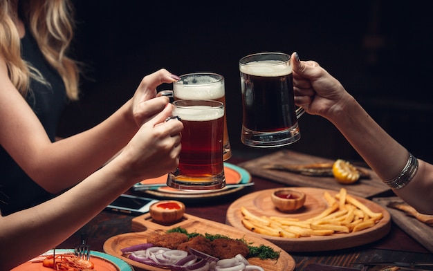 Duas mulheres na mesa de jantar com copos de cerveja.