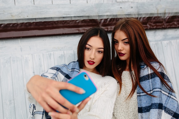 Foto grátis duas mulheres sentam no banco e fazem selfie