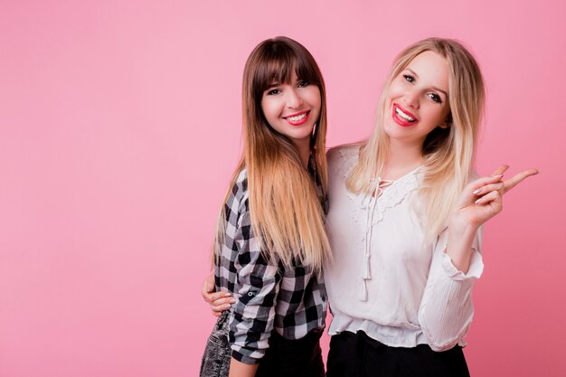 Duas mulheres sorridentes abraçando e em pé isolado