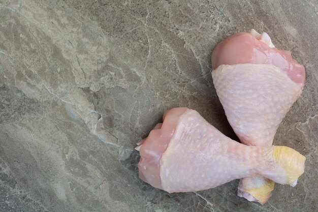 Duas pernas de frango cru no fundo de mármore. Foto de alta qualidade