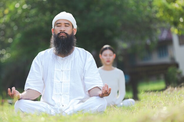 Duas pessoas em roupa branca meditando na natureza