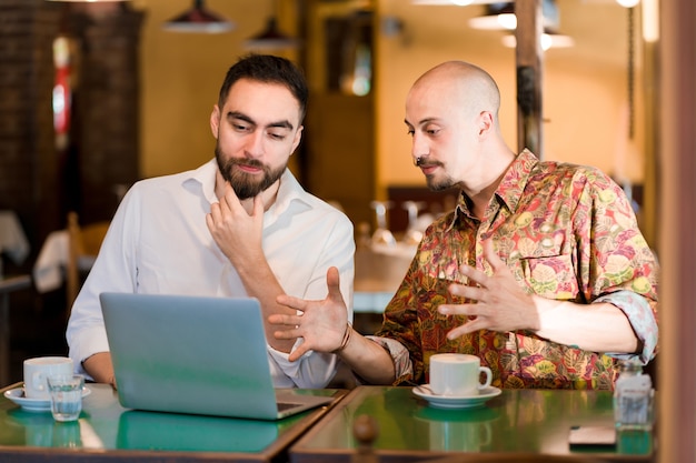 Duas pessoas usando um laptop em uma reunião em uma cafeteria.