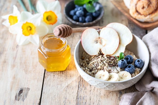 Duas tigelas de aveia ou granola com mirtilos, mel de maçã e hortelã em um fundo de madeira rústico