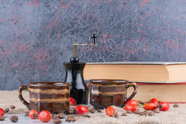 Foto grátis duas xícaras de café com feijão e roseira brava na mesa. foto de alta qualidade