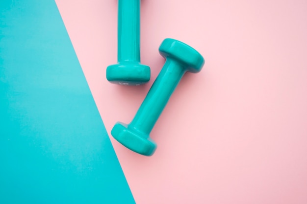 Dumbbells no fundo azul e cor-de-rosa