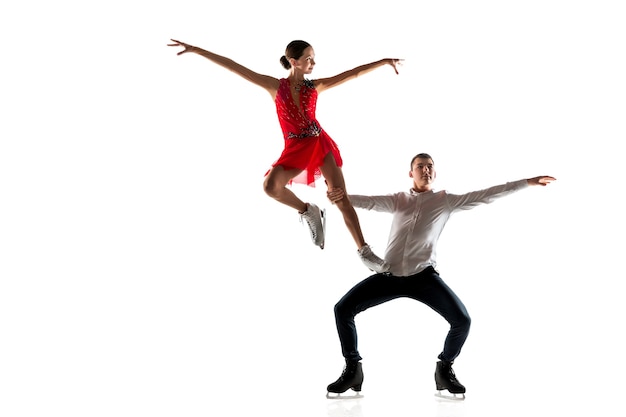 Duo de patinação artística isolado na parede branca do estúdio com copyspace. Dois desportistas praticando e treinando em ação e movimento. Cheio de graça e sem peso. Conceito de movimento, esporte, beleza.