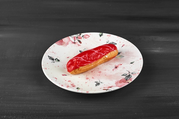 Eclair de morango em uma placa de cerâmica branca.