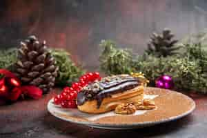 Foto grátis Éclairs deliciosos de chocolate com frutas vermelhas em fundo escuro de vista frontal