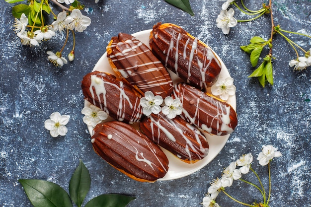 Éclairs ou profiteroles com chocolate preto e chocolate branco com creme dentro, sobremesa francesa tradicional. vista do topo.