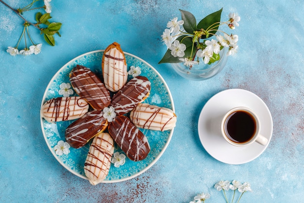 Éclairs ou profiteroles com chocolate preto e chocolate branco com creme dentro, sobremesa francesa tradicional. vista do topo.