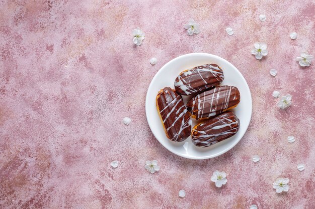 Eclairs ou profiteroles com chocolate preto e chocolate branco com creme para dentro, sobremesa francesa tradicional. Vista superior.