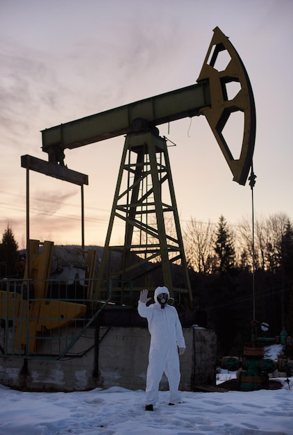 Ecologista em pé perto de jack de bomba de poço de petróleo