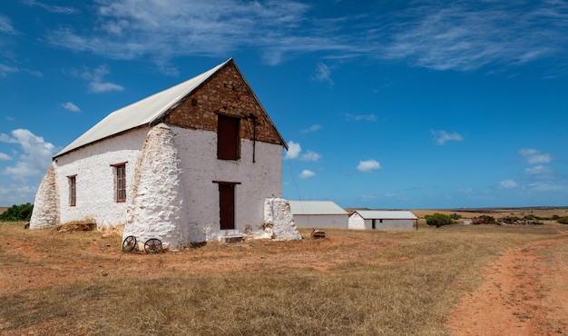 Edifício branco em um campo de uma fazenda em uma área rural sob o céu nublado