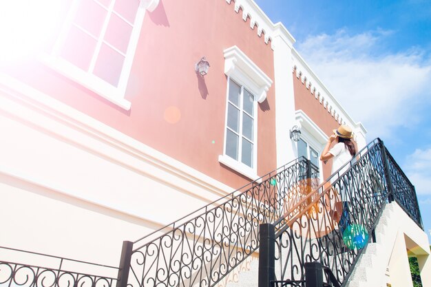 Edifício clássico com perspectiva atractiva e mulher turística em vestido branco e chapéu