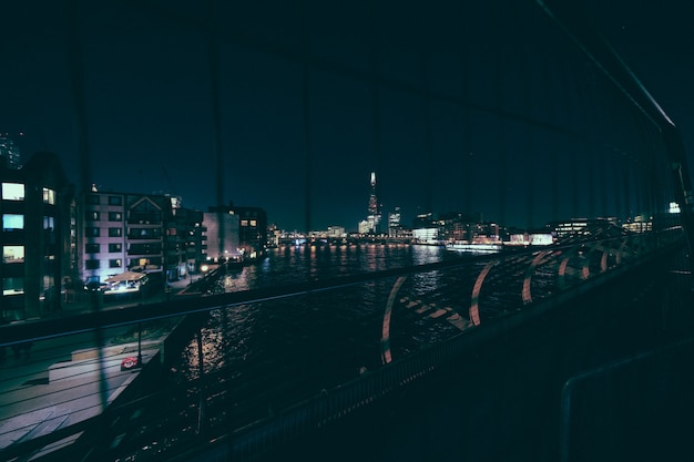 Foto grátis edifício da cidade perto da água baleado por trás das grades em uma ponte