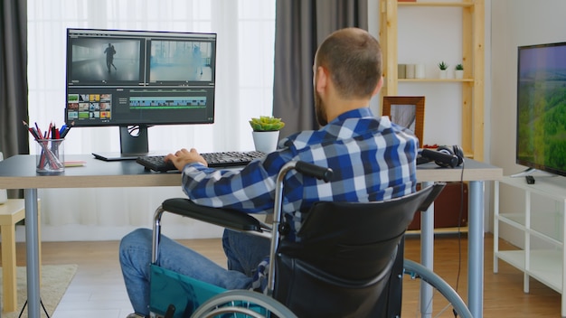 Editor de vídeo profissional em cadeira de rodas devido à deficiência motora.