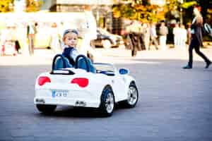 Foto grátis ei, o que há? menino pequeno bonito conduz seu primeiro carro