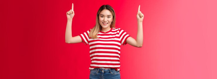 Foto grátis ei, vamos alegre jovem asiática bonita apontando as mãos para cima mostrando promoção sorrindo alegria