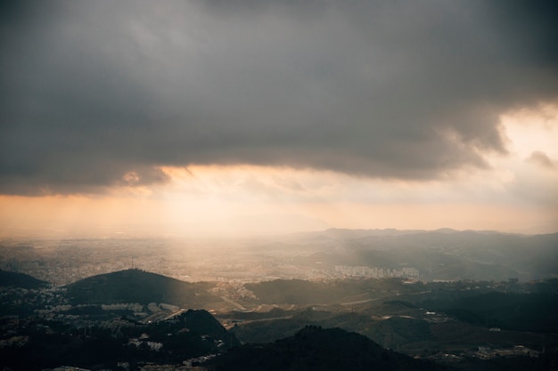 Eixo de luz que penetra através do céu escuro sobre a montanha da arquitectura da cidade